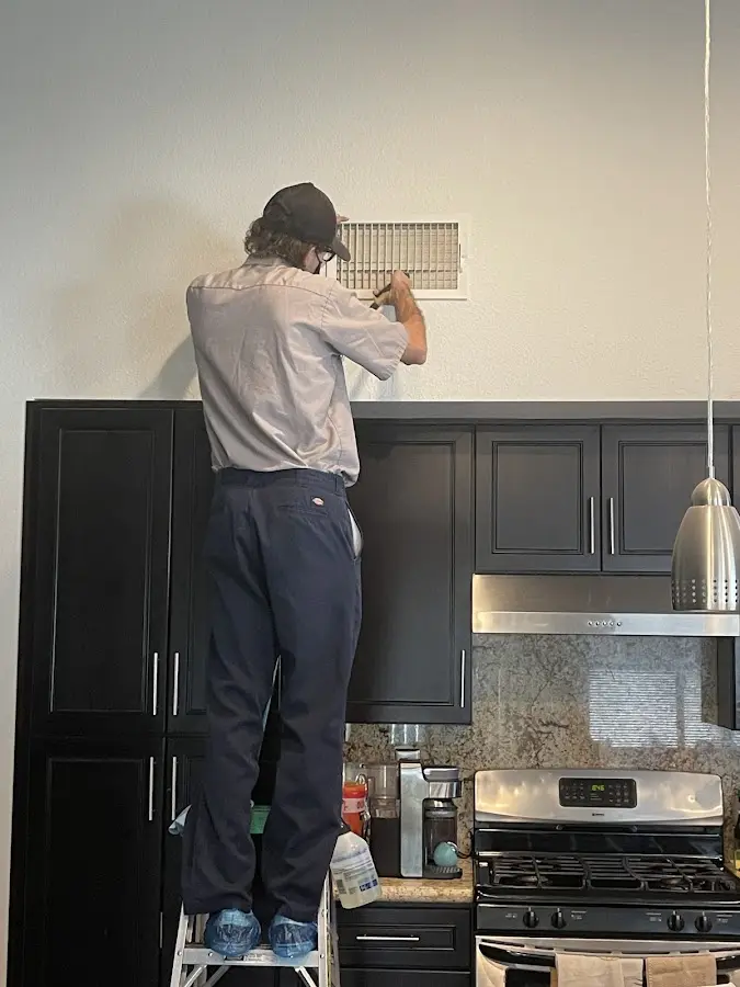 Technician inspecting an air vent during HVAC service in Winona Lake